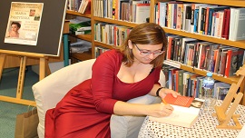 Na zdjęciu autorka apisuje dedykację do książki dla czytelników