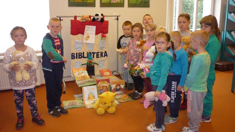 zdjęcie grupy dzieci z książkami i maskotkami misia puchatka